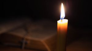 Cross with bible and candle on a old oak wooden table. Beautiful gold background. Religion concept.